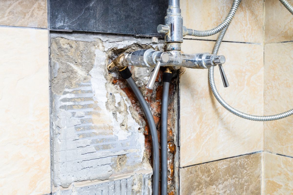 Exposed water supply pipes inside an opened wall after a pipe leak